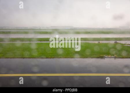 Landung am Flughafen Rotterdam Start- und Landebahn an einem regnerischen Tag, Regentropfen auf der Ebene Fenster, Hintergrund. Stockfoto
