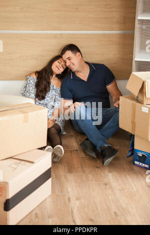 Junge glückliches Paar sitzen auf dem Boden ruhen nach dem Auspacken. Paar chillen nach Kisten Stockfoto