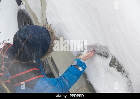 Sheffield, Großbritannien - 28 Feb 2018: Spielen im Schnee: junge Schabt Schnee aus ein Auto, da das Tier aus dem Osten griffe Sheffield in eisige Winter Wetter Stockfoto