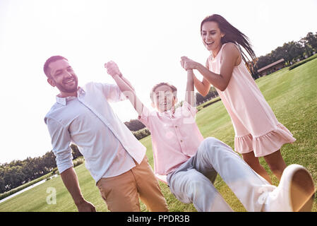 Kleben. Familie von drei Fuß auf Wiese holding Sohn Stockfoto