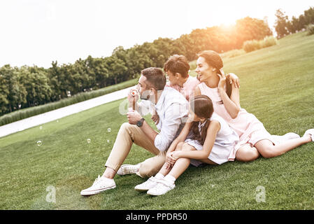 Kleben. Familie von vier Sitzen auf einer Wiese blasen Blase Stockfoto