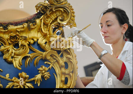 Dipl-Restaurator (konservator mit Diplom) Maria Gimenez Prades aus München arbeitet im Marstallmuseum in Schloss Nymphenburg auf der zweiten Nymphe Schlitten von König Ludwig II., der 1881 für seine Nacht Fahrten vorgenommen wurde. Sie reinigt und stärkt die Oberflächen. Außerdem entfernt Sie sorgfältig ehemalige Restaurationen und Übermalungen, um die Fahrzeuge wieder auf ein wahrscheinliches Original zu bringen und gut gepflegten Gesamtzustand. Stockfoto