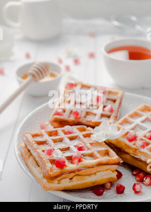 Lecker köstliche Wiener Waffeln mit Honig und Granatapfel Samen auf eine weiße Platte, hellen Hintergrund. Stockfoto