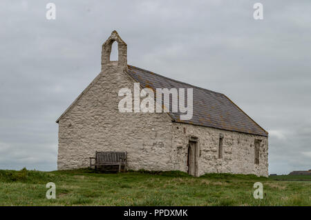 Im 12. Jahrhundert St Cwyfan Kirche, auf der kleinen Insel Gezeiten Cribinauon, auf Anglesey. Stockfoto