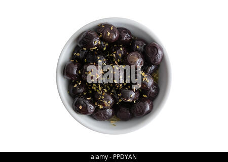 Schüssel mit lecker gewürzt grade einen schwarzen Mediterrane Oliven gewürzt mit frischen Kräutern in einem kleinen weißen ramekin isoliert auf weißem serviert. Stockfoto