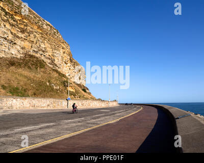 Radfahrer unter Castle Hill Klippen am Marine Drive an einem sonnigen Morgen in Scarborough North Yorkshire England Stockfoto