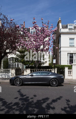 Aston Martin vor teuren Häuser mit Bäume in Blüte geparkt. Stockfoto