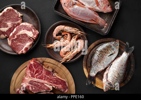 Auswahl an Fisch, Fleisch, Rindfleisch Steak und Shrimps. Gesunde Eiweißquelle und Body building Essen auf schwarzem Hintergrund. Ansicht von oben, flach. Noch immer leben Stockfoto