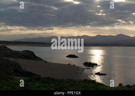 Blick von llanddwyn Island (ynys Llanddwynn), Anglesey, Nordwales, über den Strand bei Ebbe zu Snowdonia Mountains im Morgenlicht Stockfoto