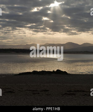 Blick von llanddwyn Island (ynys Llanddwynn), Anglesey, Nordwales, über den Strand bei Ebbe zu Snowdonia Mountains im Morgenlicht Stockfoto