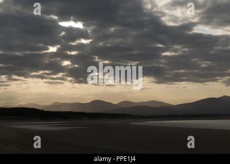 Blick von llanddwyn Island (ynys Llanddwynn), Anglesey, Nordwales, über den Strand bei Ebbe zu Snowdonia Mountains im Morgenlicht Stockfoto