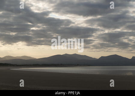 Blick von llanddwyn Island (ynys Llanddwynn), Anglesey, Nordwales, über den Strand bei Ebbe zu Snowdonia Mountains im Morgenlicht Stockfoto