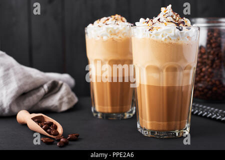 Iced Caramel latte Kaffee in einem großen Glas mit Schokolade Sirup und Sahne. Dunklen Hintergrund. Stockfoto