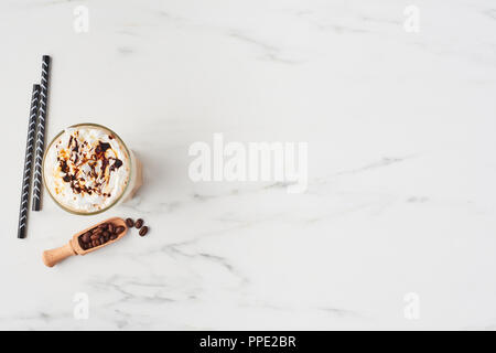 Flach der Iced Latte Kaffee in ein hohes Glas mit Karamell und Schokolade Sirup auf Schlagsahne. Weißer Marmor Hintergrund mit kopieren. Stockfoto