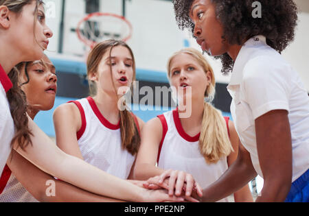 Weibliche High School Basketball Spieler Hand in Hand im Team sprechen mit Trainer Stockfoto