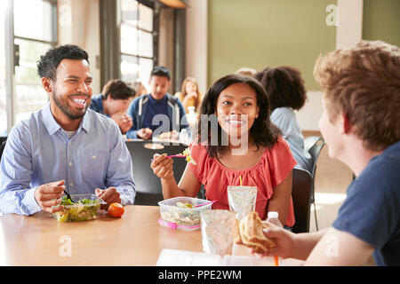 Lehrer und Schüler das Mittagessen in der High School Cafeteria während der Aussparung Stockfoto