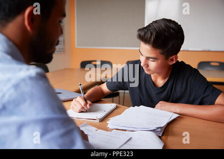 High School Tutor Die männlichen Kursteilnehmer Einzelunterricht am Schreibtisch Stockfoto