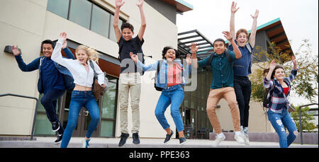 Gruppe von Schülern das Springen in die Luft außerhalb der Hochschule Gebäude Stockfoto