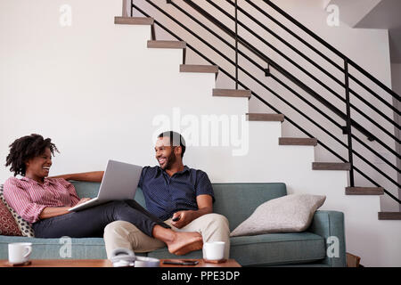 Paar sitzt auf einem Sofa zu Hause mit Frau mit Laptop Stockfoto