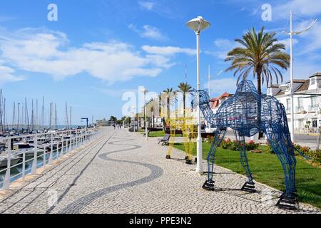 Metallrahmen Kamele entlang der Av Da Republica mit Yachten und Boote im Yachthafen auf der rechten Seite festgemacht, Vila Real de Santo Antonio, Algarve, P Stockfoto