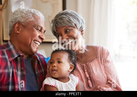 Großeltern auf dem Sofa mit Baby Enkelin zu Hause sitzen Stockfoto