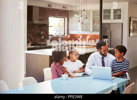 Die Eltern sitzen um den Tisch zu Hause hilft Kindern bei den Hausaufgaben Stockfoto