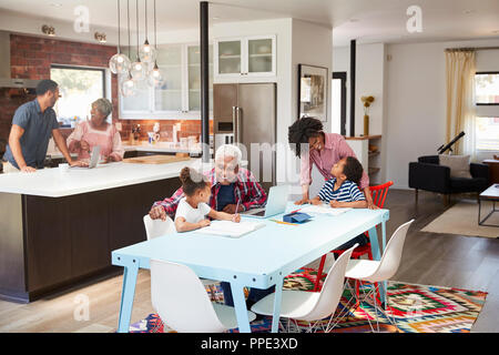 Kinder Hausaufgaben in geschäftigen Multi Generation Familie Home Stockfoto