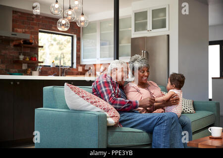 Großeltern auf dem Sofa mit Baby Enkelin zu Hause sitzen Stockfoto