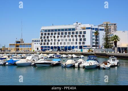 Kleiner Motor Yachten in der Marina mit einer Waterfront Hotel an der Rückseite, Faro, Algarve, Portugal, Europa günstig. Stockfoto