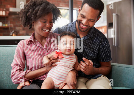 Familie mit Baby Tochter entspannt auf einem Sofa zu Hause zusammen Stockfoto