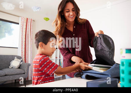 Mutter im Schlafzimmer helfen Sohn Pack Tasche bereit für die Schule Stockfoto