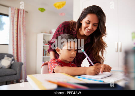 Mutter hilft Sohn mit Hausaufgaben sitzen am Schreibtisch im Schlafzimmer Stockfoto