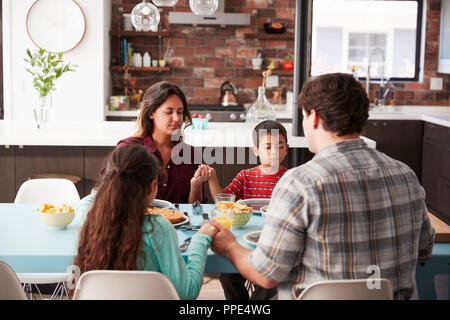 Familie Beten vor dem Essen um den Tisch zu Hause. Stockfoto