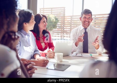 Lächelnd Geschäftsmann im Gespräch mit Kollegen in einem Meeting Raum Stockfoto
