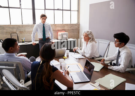 Junge männliche Manager steht das Hören bei einem Treffen mit Team Stockfoto