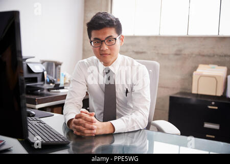 Junge asiatische Geschäftsmann im Büro, zu Kamera suchen Stockfoto