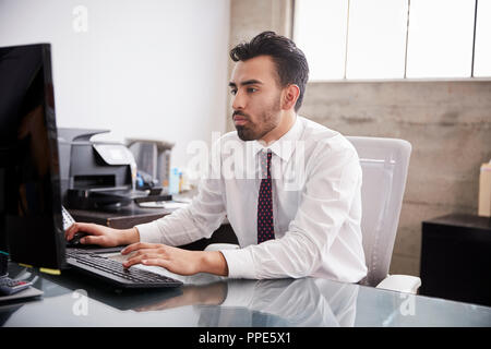 Junger spanischer Geschäftsmann mit Computer in einem Büro Stockfoto