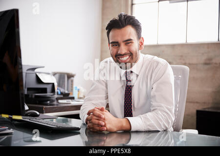 Junger spanischer Geschäftsmann im Büro Schreibtisch Lächeln für die Kamera Stockfoto