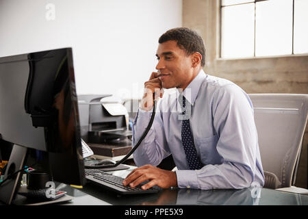Geschäftsmann bei einer Verwendung von Telefon und Computer Büro Schreibtisch Stockfoto