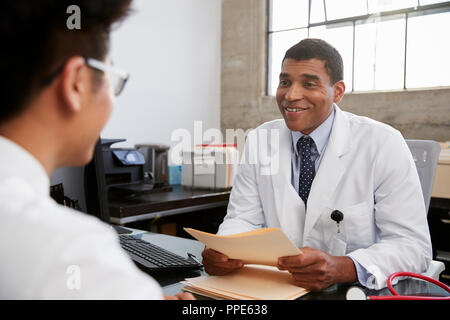 Gemischte Rasse männlicher Arzt holding Dokumente in Patienten treffen Stockfoto