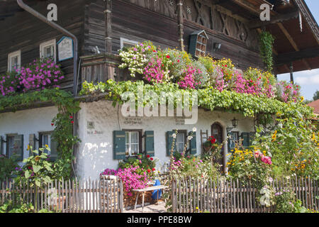 Herrliche alte Bauernhaus mit schönen Blumen im Haus und im Garten: Die obere Etage ist eine Holzkonstruktion (aufwendige Bau log). Stockfoto