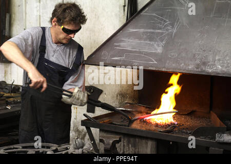 In der Kursschmiede auf dem Gelände der Kultfabrik im Kunstpark Ost, die sich die Grundlagen der Schmiedekunst erlernen können. Dargestellt, Inhaber Stefan Szekessy Heizung Bügeleisen am offenen Feuer. Stockfoto