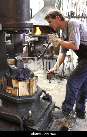 In der Kursschmiede auf dem Gelände der Kultfabrik im Kunstpark Ost, die sich die Grundlagen der Schmiedekunst erlernen können. Dargestellt, Inhaber Stefan Szekessy am Hammer mit Riemenantrieb aus den dreißiger Jahren. Stockfoto