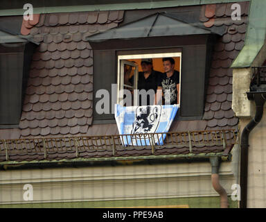 Zwei Bewohner mit Lion Flagge folgen der Regionalliga Süd Derby aus ihrem Fenster: FC Bayern München II - TSV 1860 München (2:0) beim städtischen Stadion in der gruenwalder Straße in München. Stockfoto