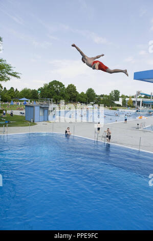 Badegast einen Sprung von einem 10 Meter hohen Turm im Michaelibad in München. Auch wenn die Badewanne ist überfüllt, während des Sprungs ist allein mit der Angst und den Nervenkitzel, und allein im Pool, dann werden durch die Mitarbeiter der Badewanne überprüft. Stockfoto