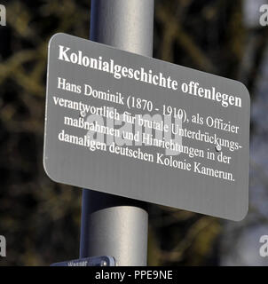 Ein zusätzliches Schild mit den Worten "die koloniale Geschichte enthüllt' ist neben dem Schild Dominikstrasse befestigt. Das Zeichen enthält Informationen über die grausame Unterdrückung der Herero des Deutschen Reiches in der ehemaligen Kolonie Deutsch-Südwest-Afrika. Stockfoto