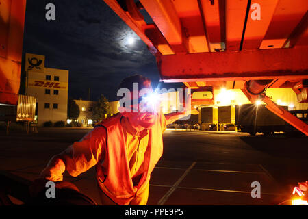 Bericht: DHL Paketzentrum in Aschheim - ein halb Treiber prüft des Anhängers vor der Fahrt zu Baden-württemberg. Stockfoto