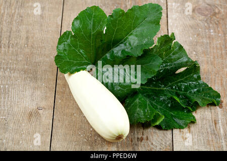 Frische Zucchini mit grünen Blättern auf hölzernen Hintergrund Stockfoto