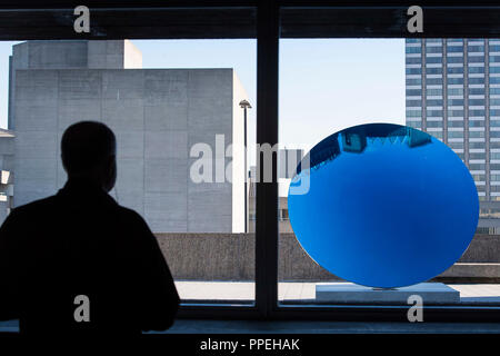 Ein Mann Ansichten ky Spiegel, Blau, 2016" von Anish Kapoor, während einer Pressekonferenz für die Ausstellung: Space Laufräder in der Hayward Gallery, Southbank Centre, London. Stockfoto