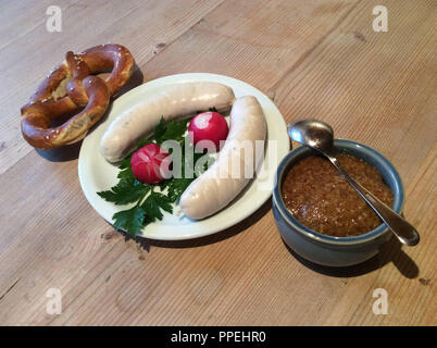 Weißwurst Snack oder Frühstück mit Brezel, Brötchen, Petersilie und Senf auf einem rustikalen Holztisch. Stockfoto